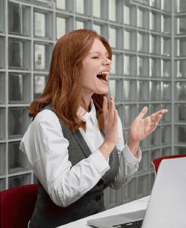Une participante rit et tape dans les mains, montrant sa joie lors d'un jeu PopCorn Garage dans un bureau pendant un team building.