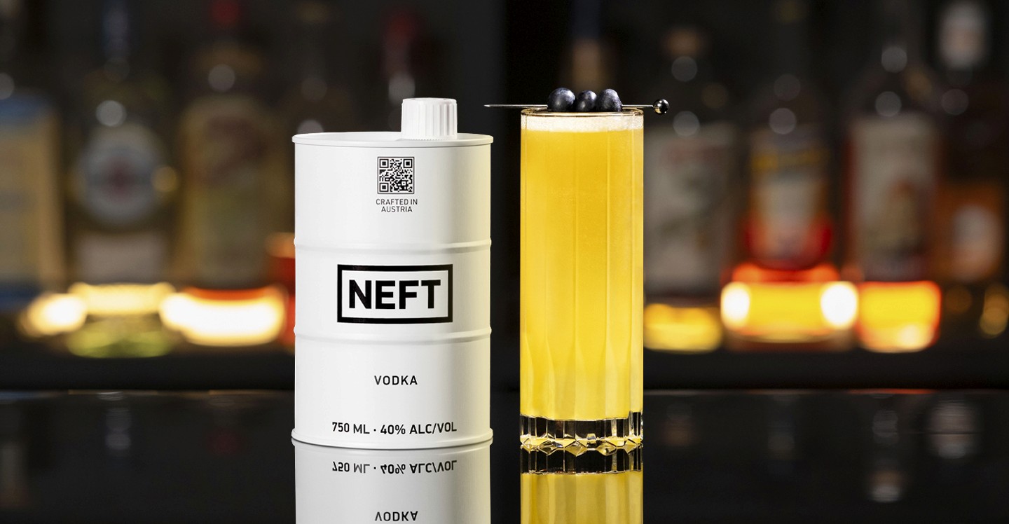A NEFT Barrel and a glass of Wings of Passion Fruit on a bar counter.