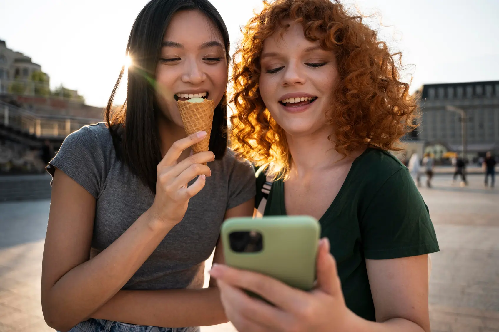 Two friends laughing while looking at a phone