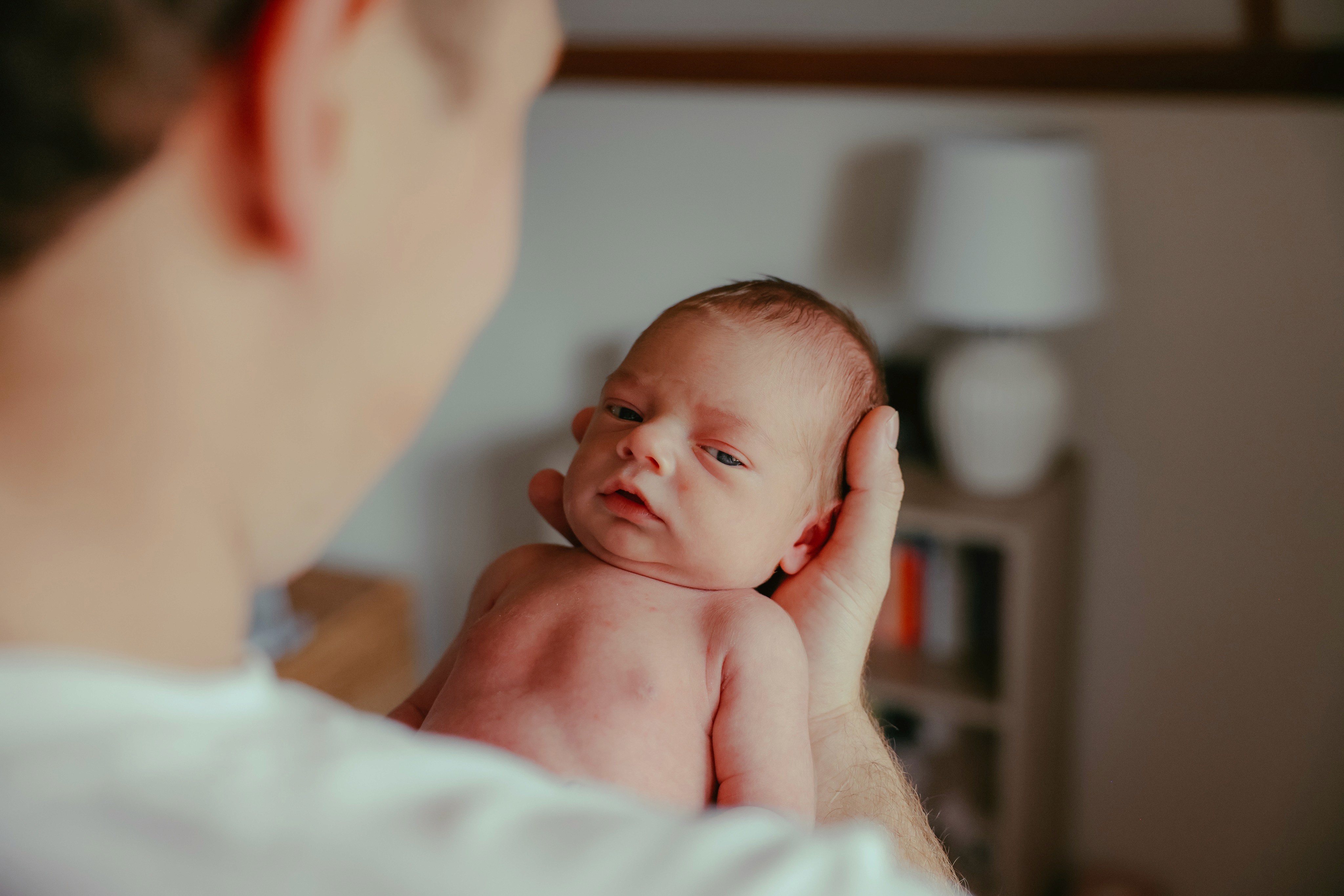 Newborn looking over his father's shoulder at home