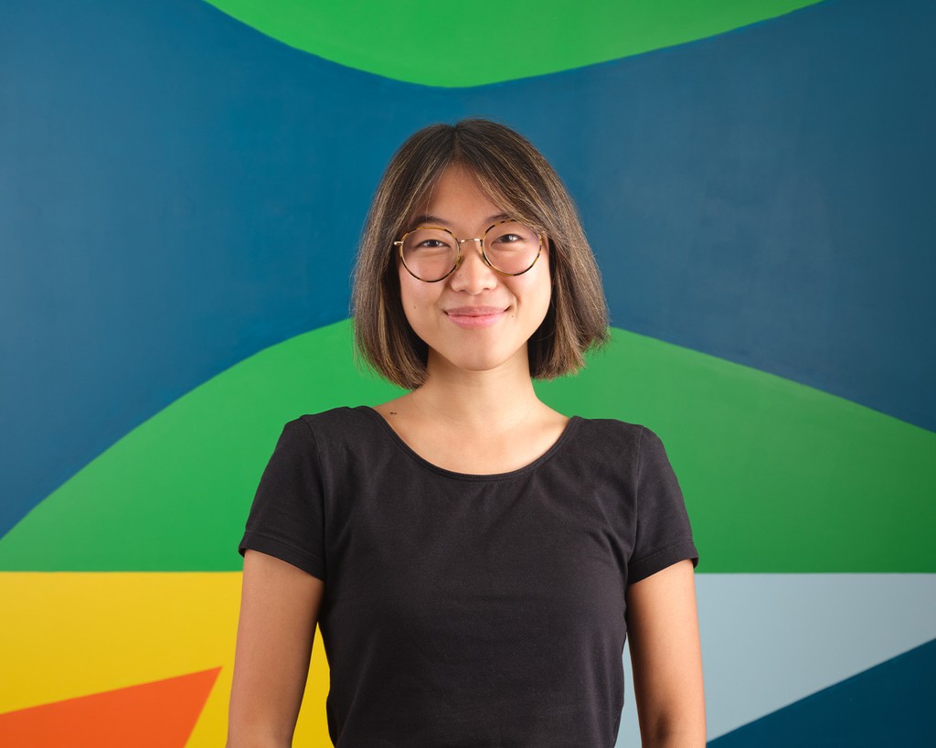 Portrait of Lisa Qin standing in front of a colourful mural