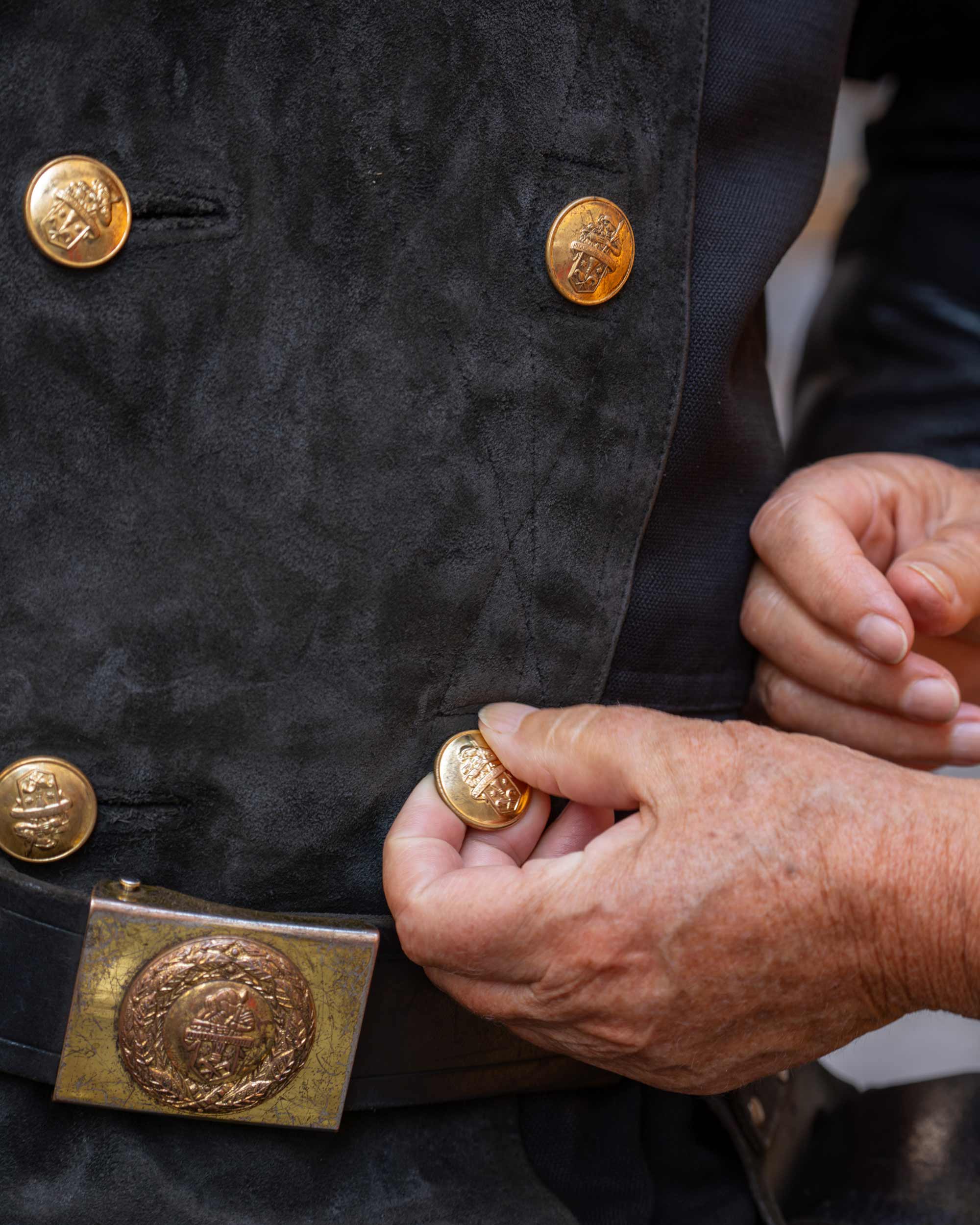 Person adjusts ornate buttons on a uniform, for Zentralverband-Deutscher-Schornsteinfeger