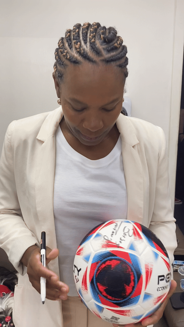 Brazilian football legend Formiga signs a soccer ball for young athletes from the NGO Em Busca de Uma Estrela.