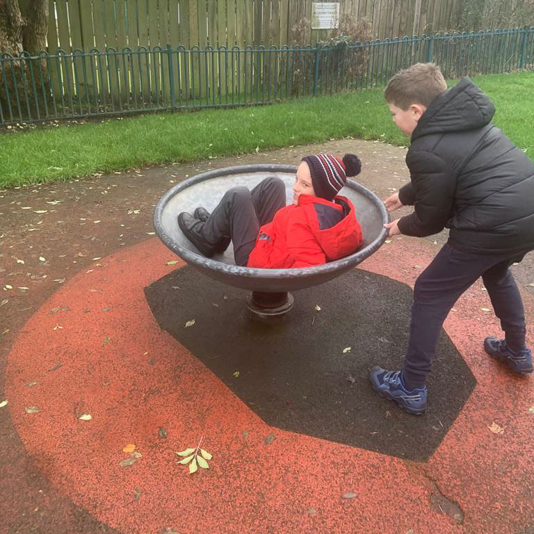 Two children play in the park in a spinning wheel