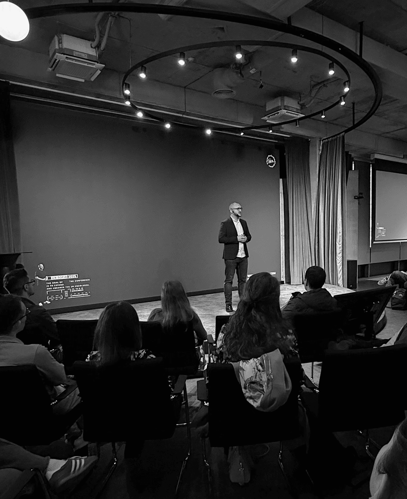 Image of UX design leader presenting on enterprise UX strategy and design systems to a packed audience.