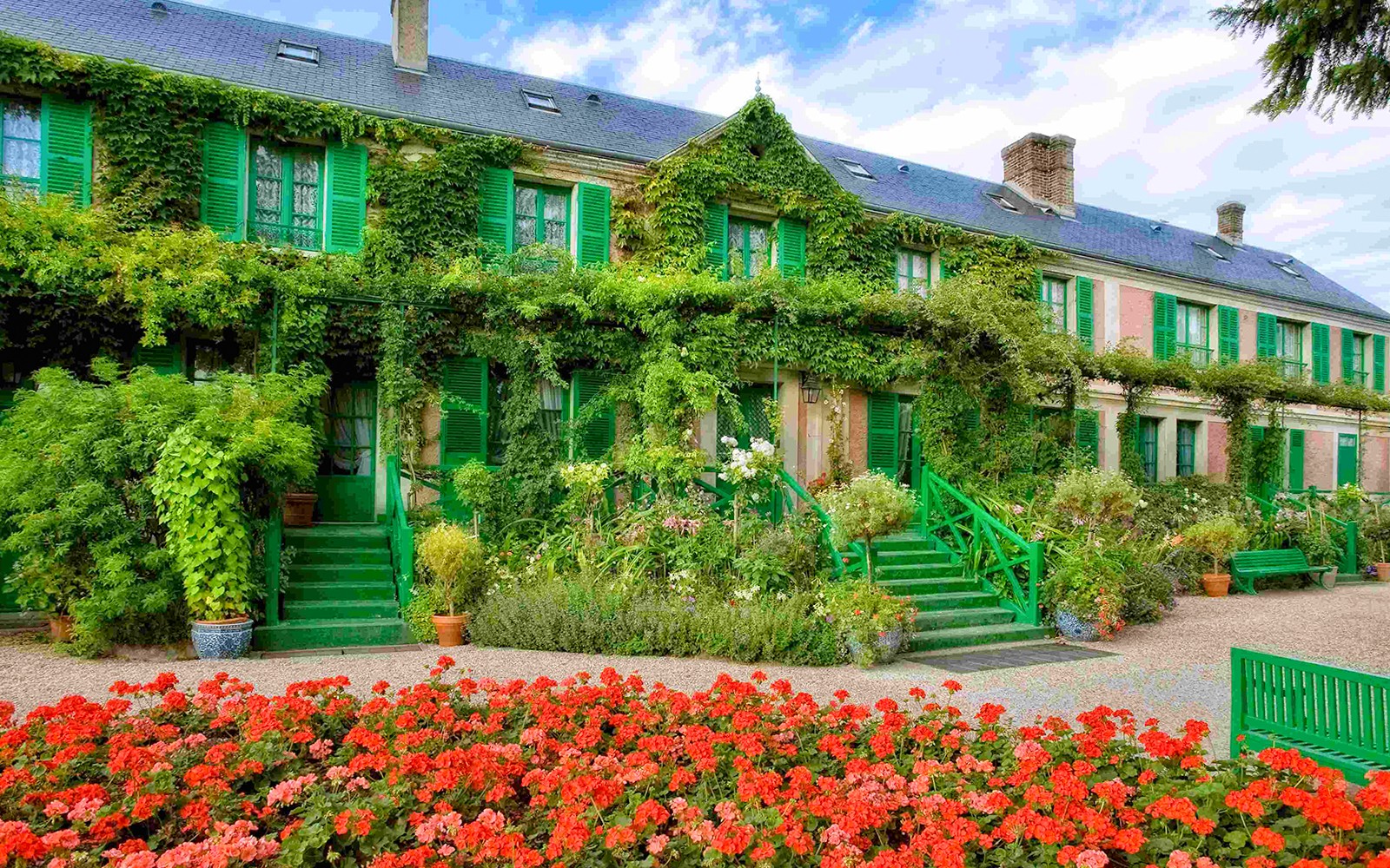 Giverny Gardens with vibrant flowers and ivy-covered house, part of Versailles Palace & Giverny Gardens Tour.
