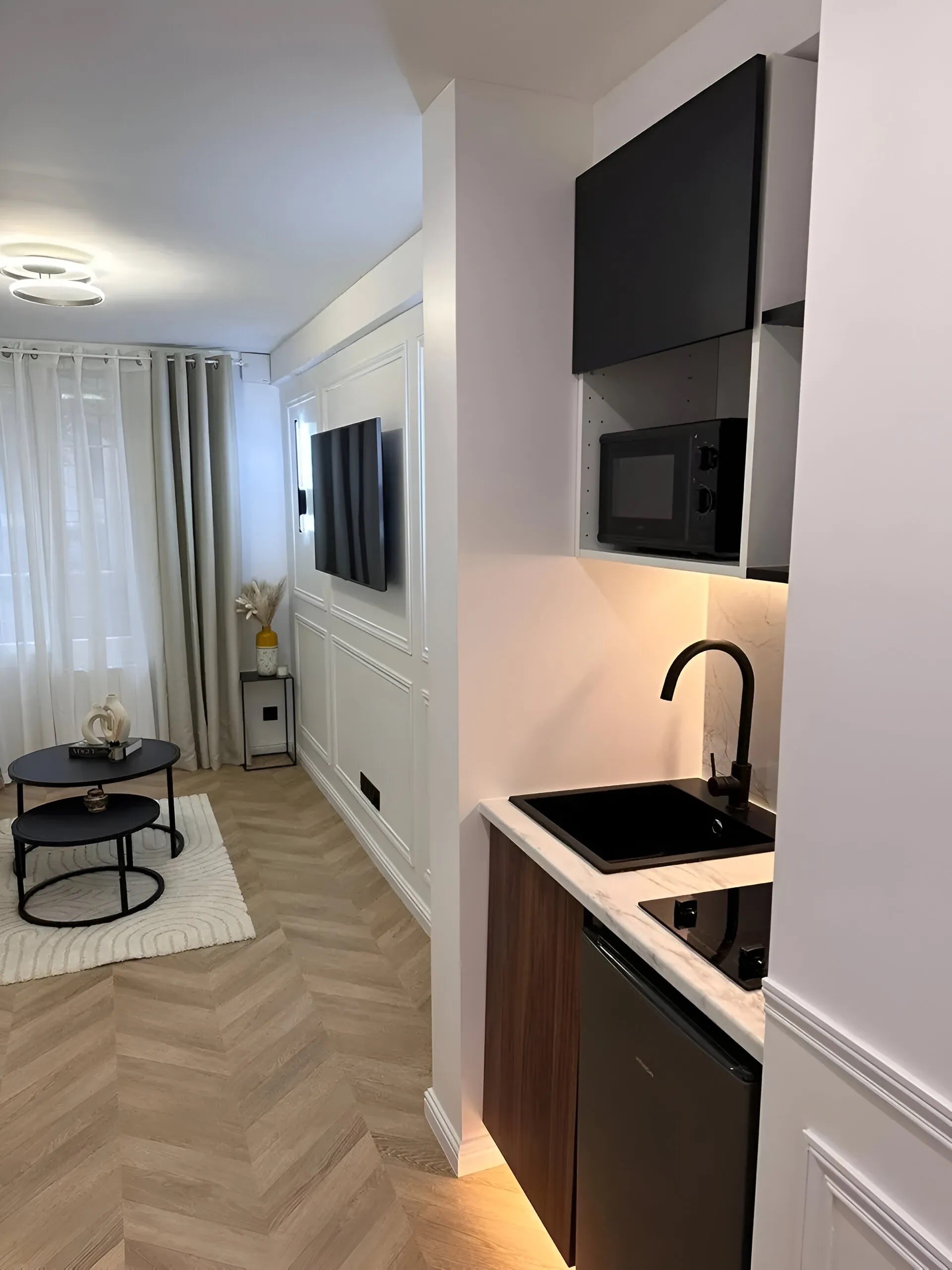 Vue d'ensemble de l'optimisation millimétrée entre le coin cuisine et l'espace détente dans un studio parisien.
