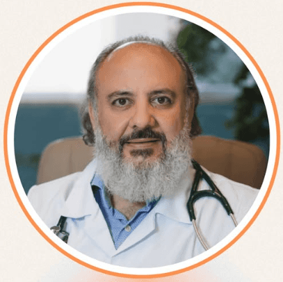 Female educator teaching an online class from her desk, speaking into a microphone while viewing a grid of students on her computer screen.