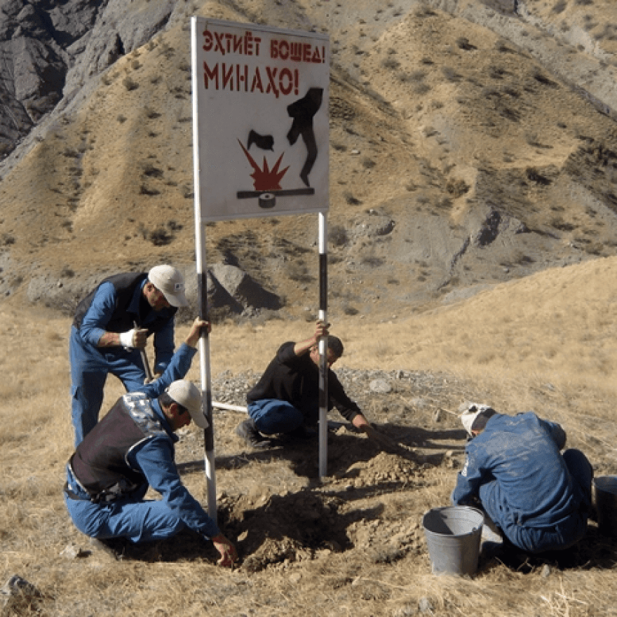 Workers installing a sign in a mountain landscape.