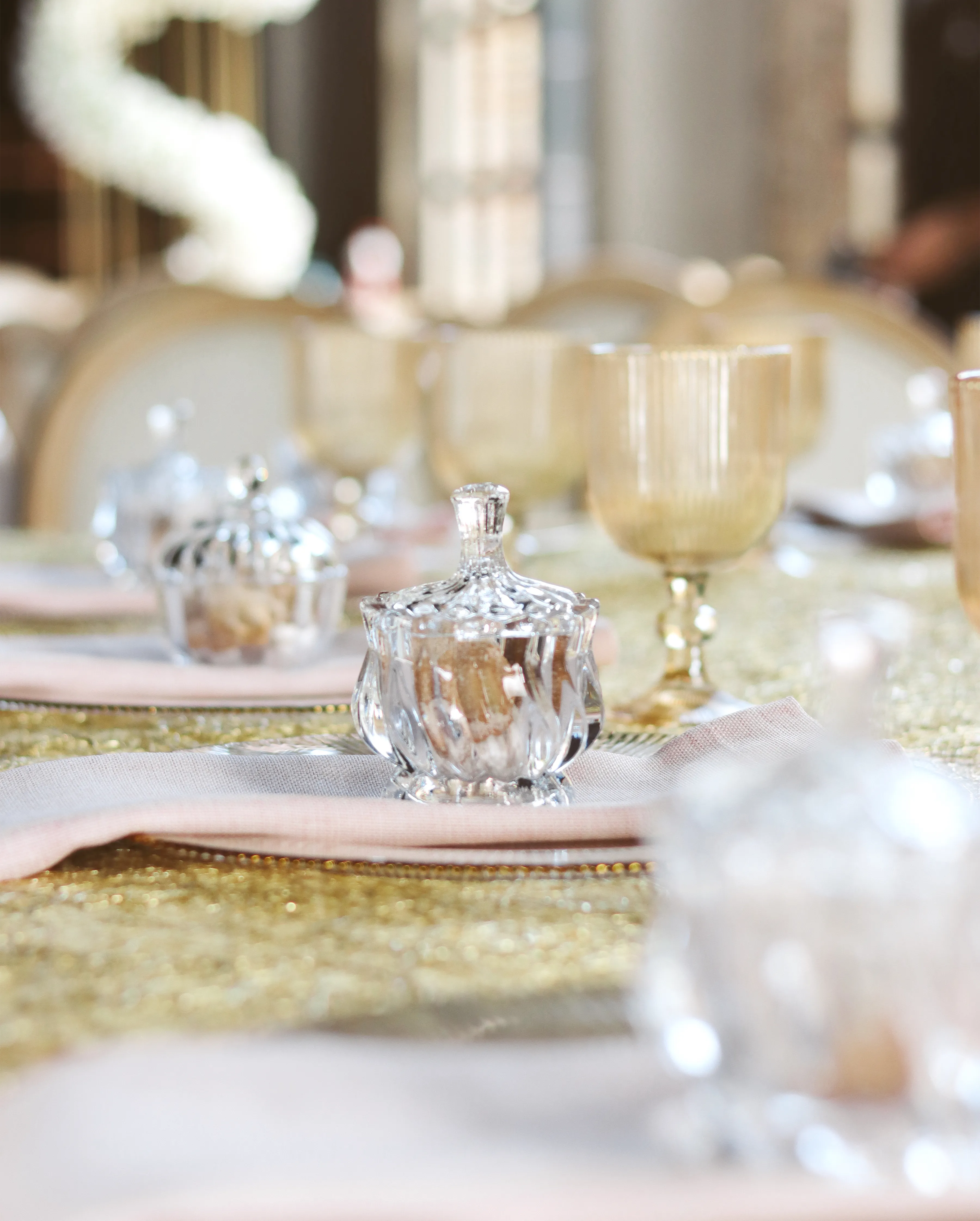 Detalle de mesa elegante con frascos de cristal y copas doradas