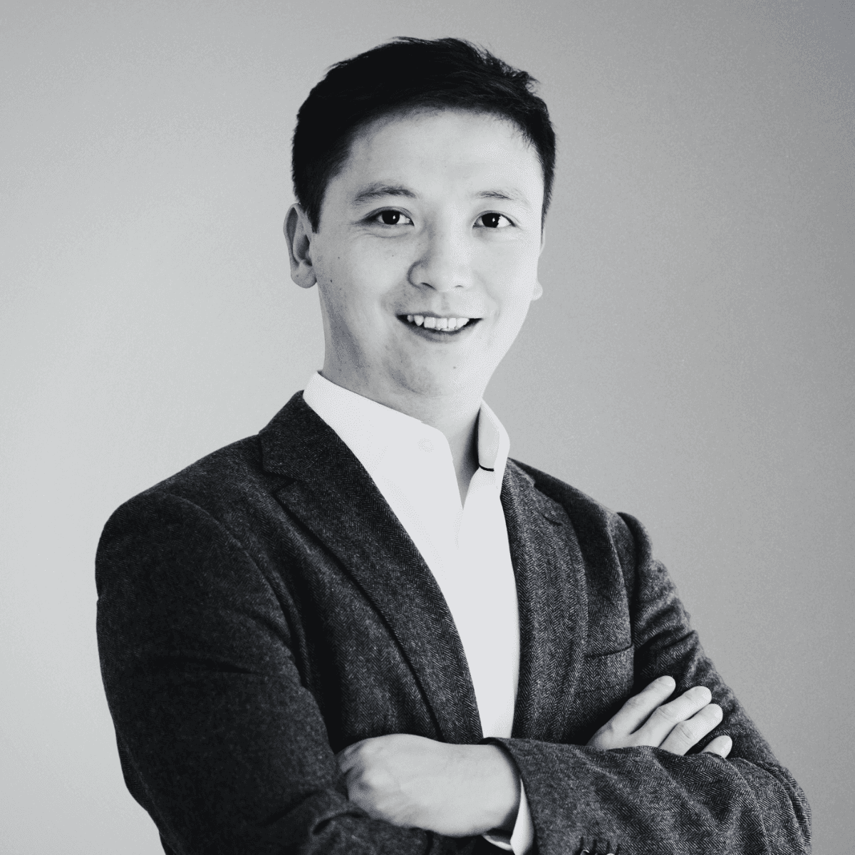 black and white photo of the upper part of a asian man in a suit with white shirt and his arms crossed. this is the COO of BeyondTrucks, Paul Xie