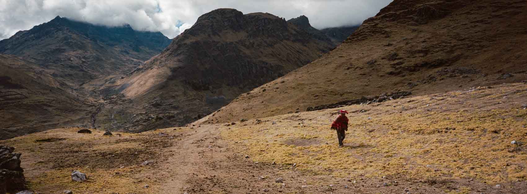 Panoramic film photograph taken near Machu Picchu elevation, showing a local hiking in traditional Peruvian clothing in the Andean mountains, highlighting everyday life at high altitude.
