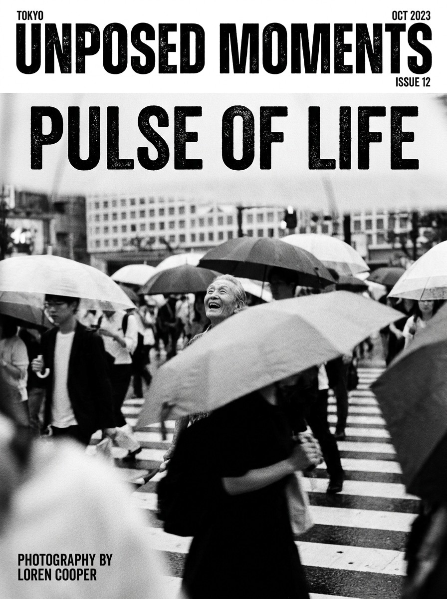 Unposed Moments zine cover showing black and white street photography of a crowded city crosswalk with people holding umbrellas.