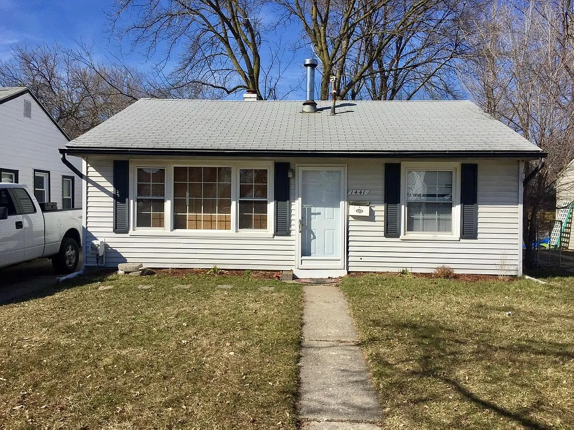 A modern brick house with a two-car garage, well-manicured lawn, and clear blue sky in the background.