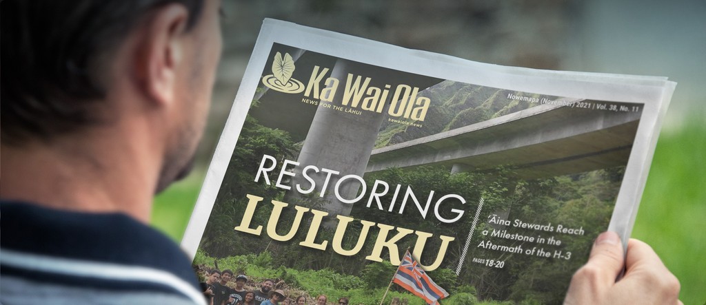 A reader holding a printed issue of Ka Wai Ola, with the cover story “Restoring Luluku.”