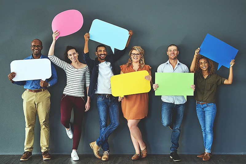 Group of six people holding coloured speech bubbles