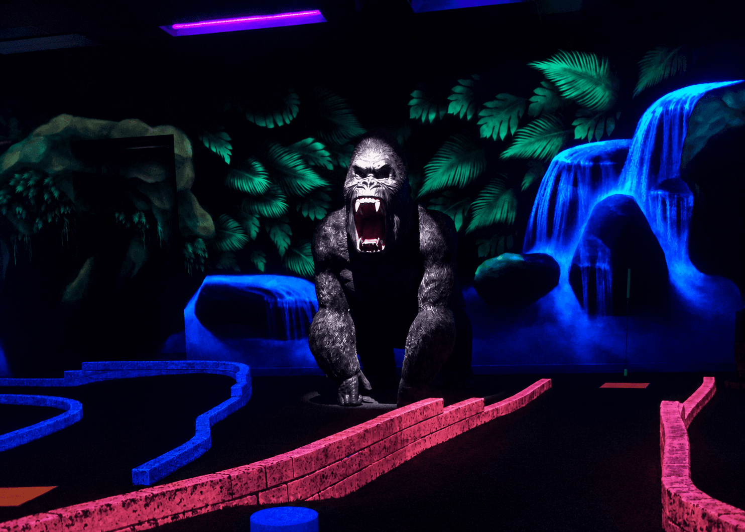 Neonbelyst minigolfbana med gorilla och vattenfall