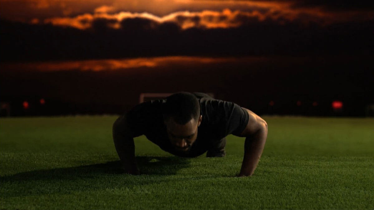 A man strength training on soft synthetic XL Pro Sports Field turf by AGL Grass.