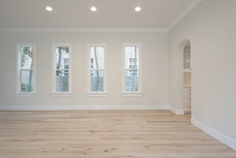 Spacious dining room with oak floors, recessed lighting, and multiple windows in Bonita Canyon Remodel.