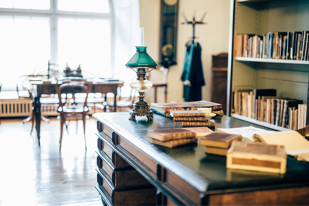 Vintage books and a desk lamp on a traditional library table, reflecting long-term accounting, financial reporting, and stewardship for private wealth structures.