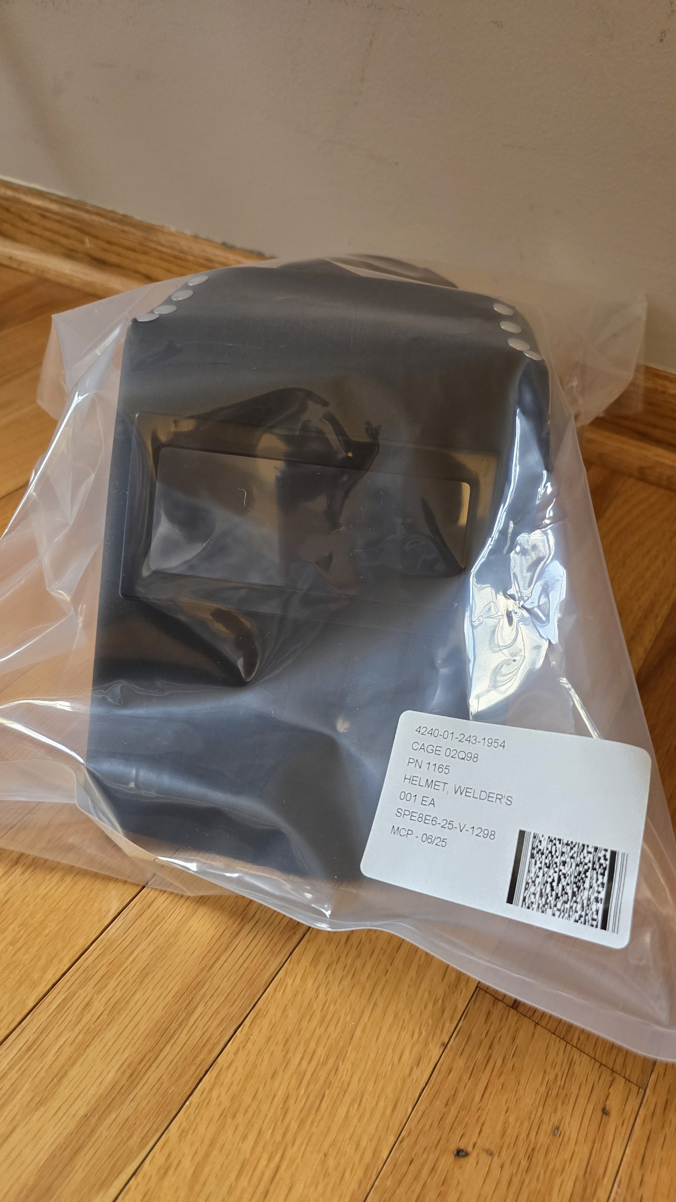 A smiling woman with her arms crossed, standing against a dark green background. She has long, dark hair.