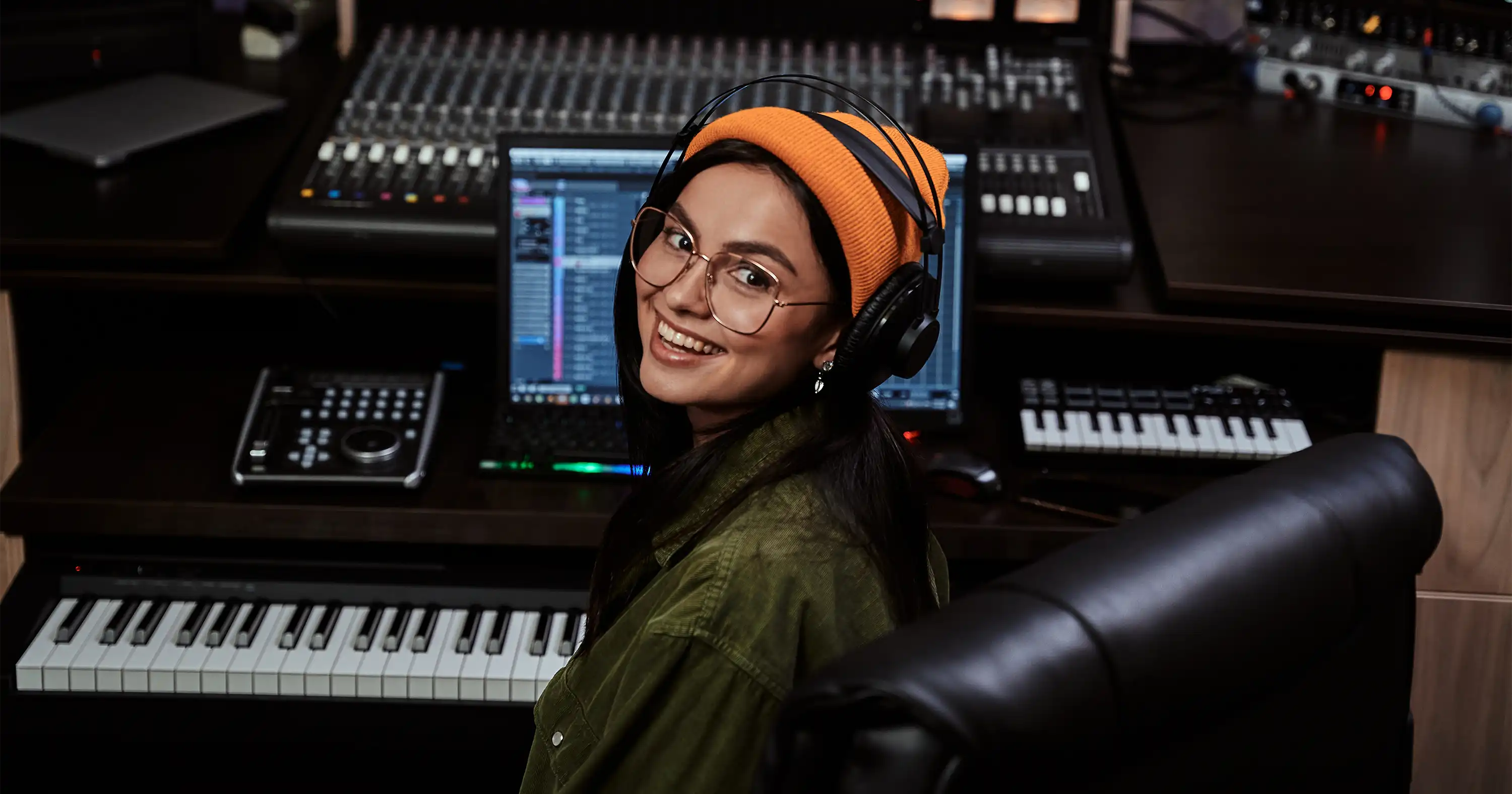 a female producer sitting in front of a keyboard and digital audio workstation