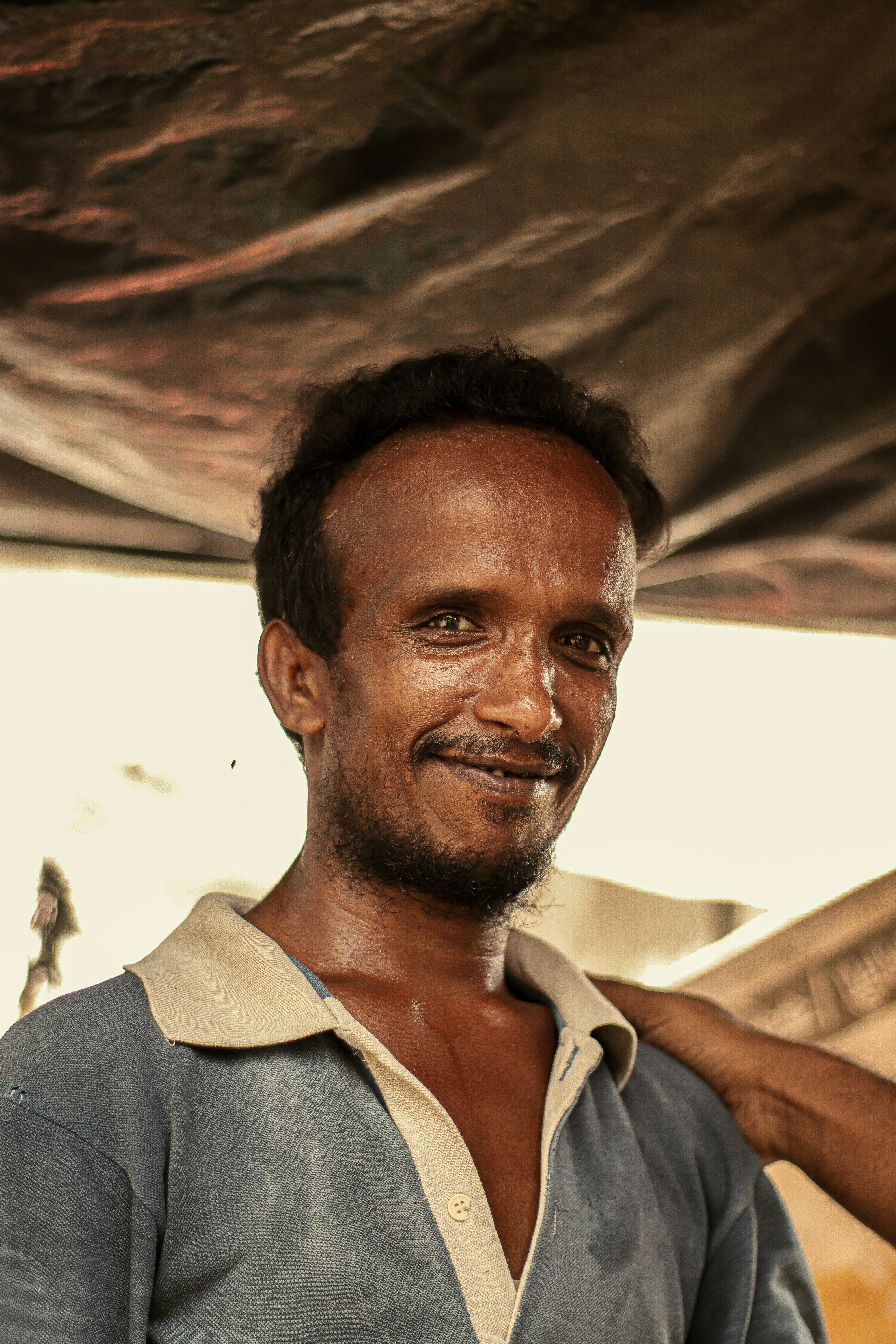 a man standing under a tarp with a smile on his face