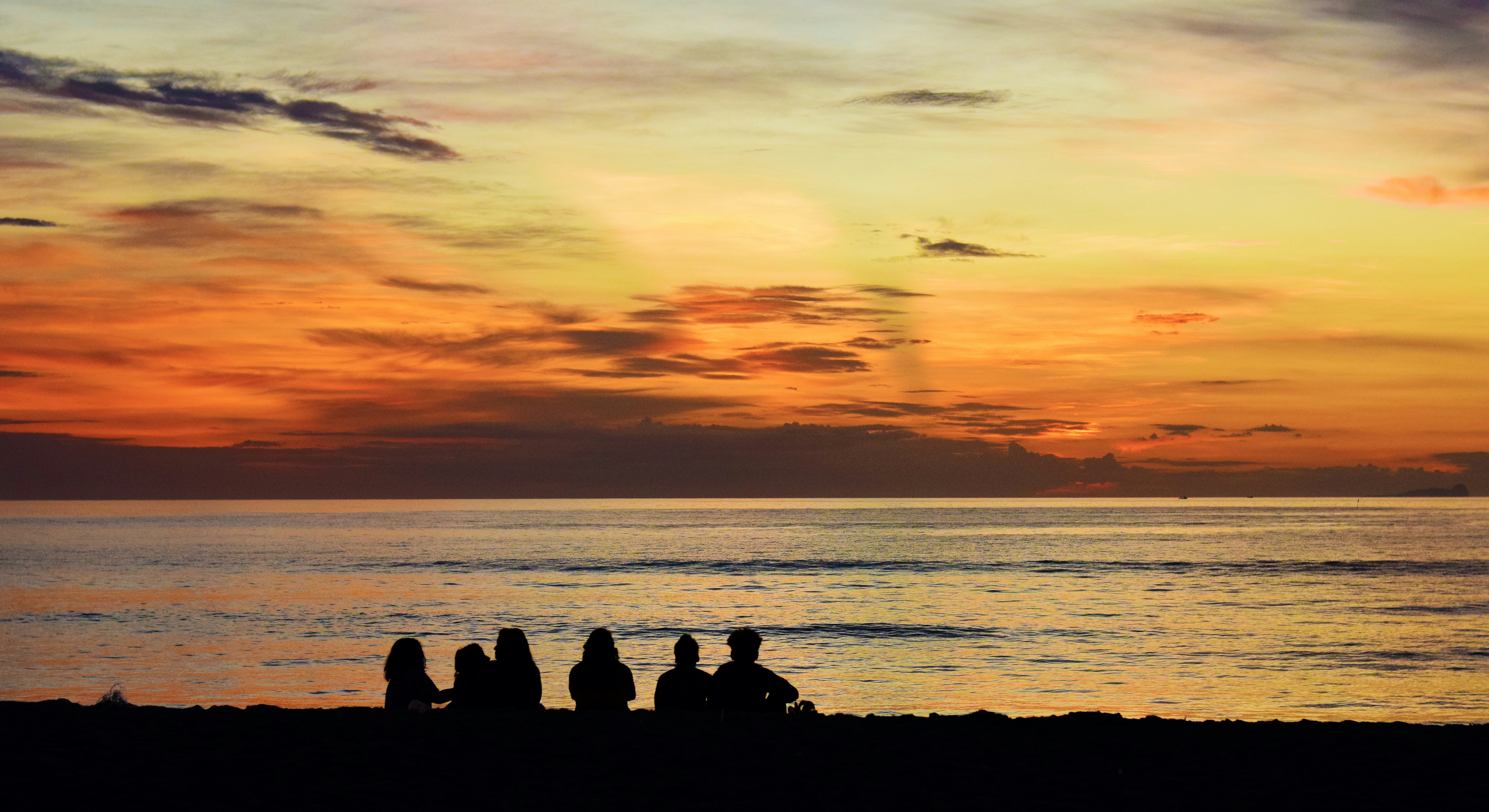 A group of people sitting on top of a sandy beach