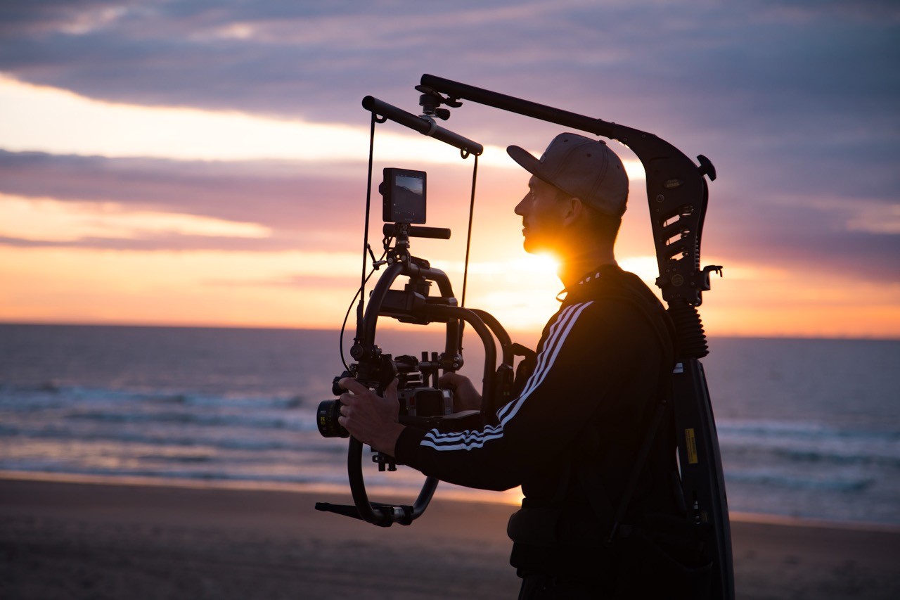 Stokedhouse videographer capturing the magic with a gimbal on the beach at sunset
