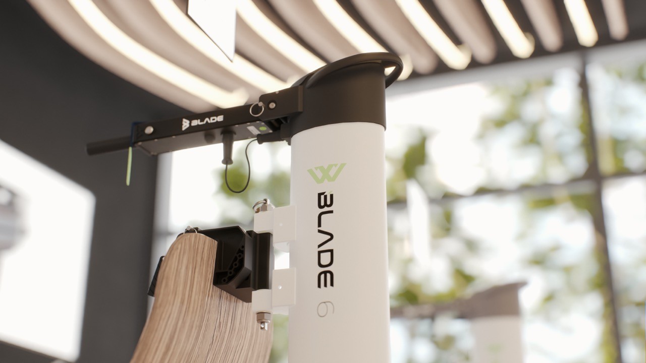 Detail view of the Blade 6 electric outboard motor's tiller arm and white wood-clamp mount, displayed indoors beneath a slatted wooden ceiling with ambient lighting.