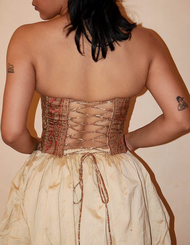 Raina is our one-of-a-kind four-panel corset, handcrafted in-house using a brown ptrinted vintage silk saree. The structured silhouette features V-cut detailing at the front, along with lace-up panels on both the front and back, allowing for a flexible fit that beautifully cinches and shapes the body. Raina is a quiet ode to craft, care, and conscious making.