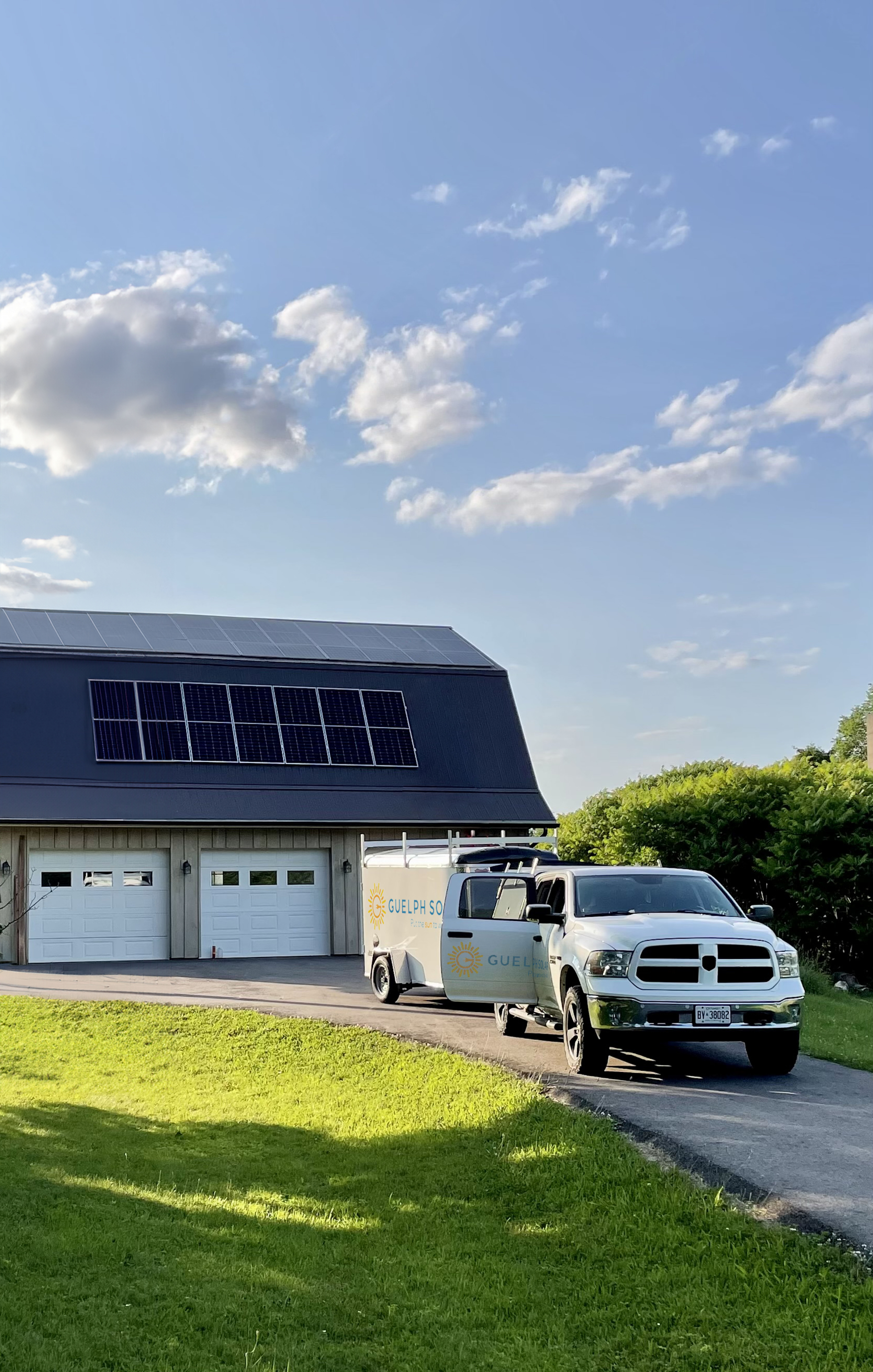 A barn with a solar panels on the roof and a Guelph Solar pickup truck parked on the driveway.