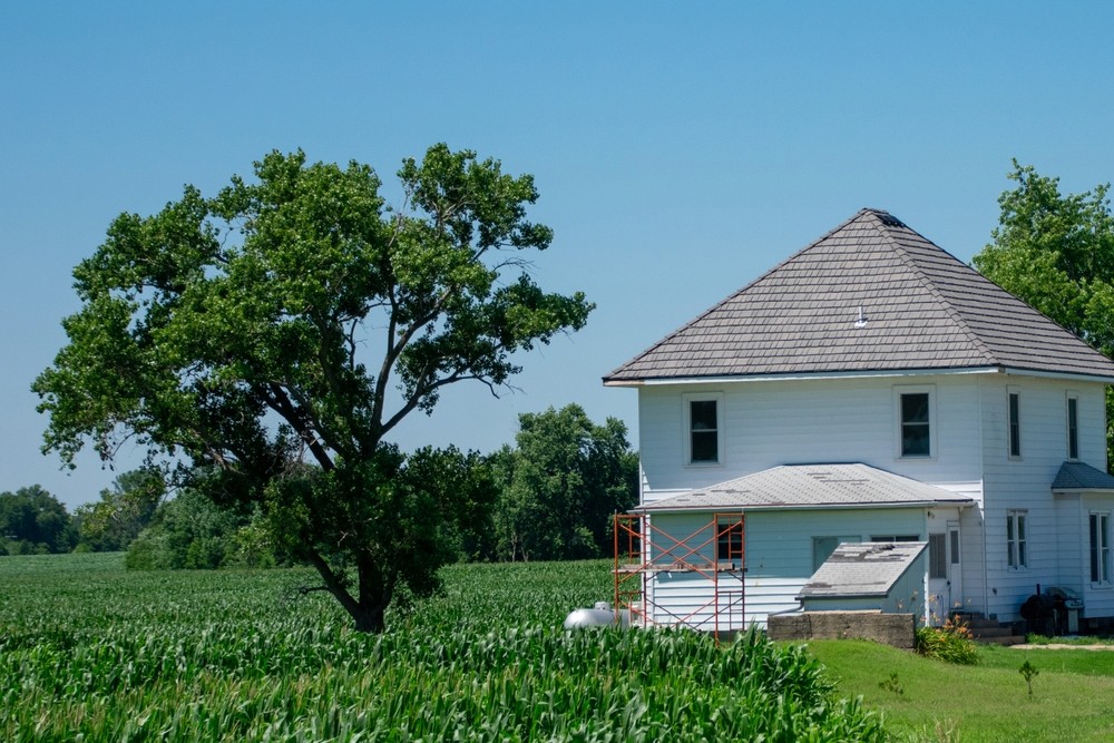 White farmhouse with pyramid roof beside a cornfield in indiana