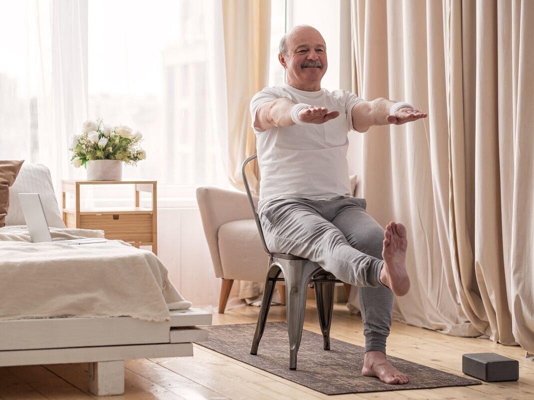 senior man doing chair exercises to lose weight in his bedroom at home