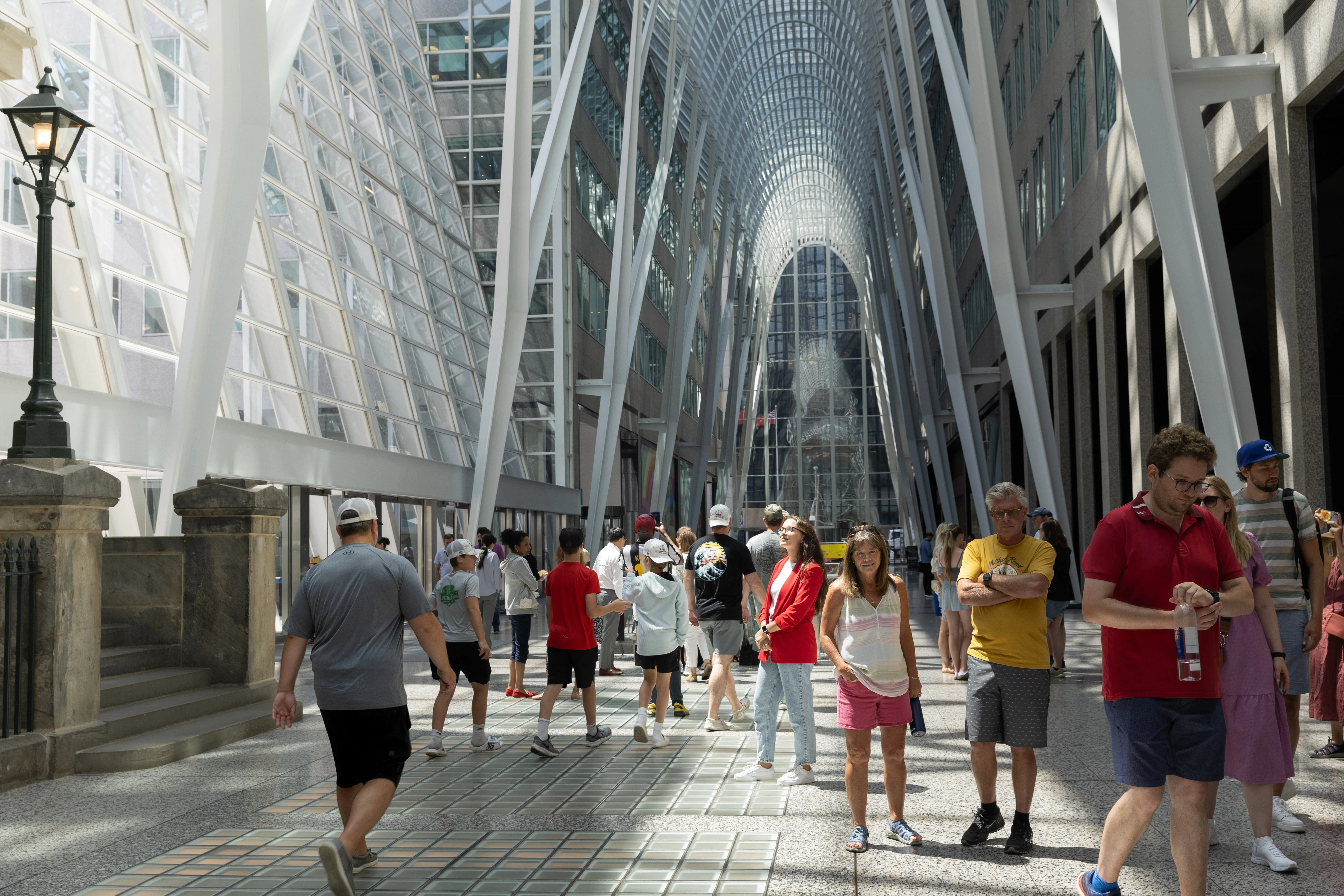 Pessoas caminhando no Brookfield Place em Toronto, com arquitetura moderna e teto de vidro iluminado.
