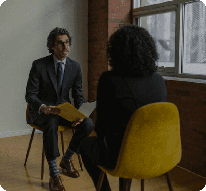 A man in suit facing a woman in a like interview session