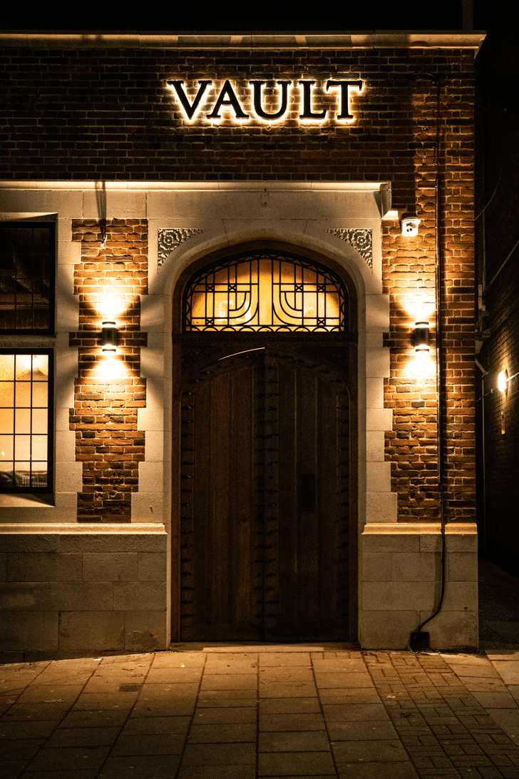 he exterior of Vault Shenfield at night, with warm lighting, a stylish entrance, and a welcoming atmosphere.