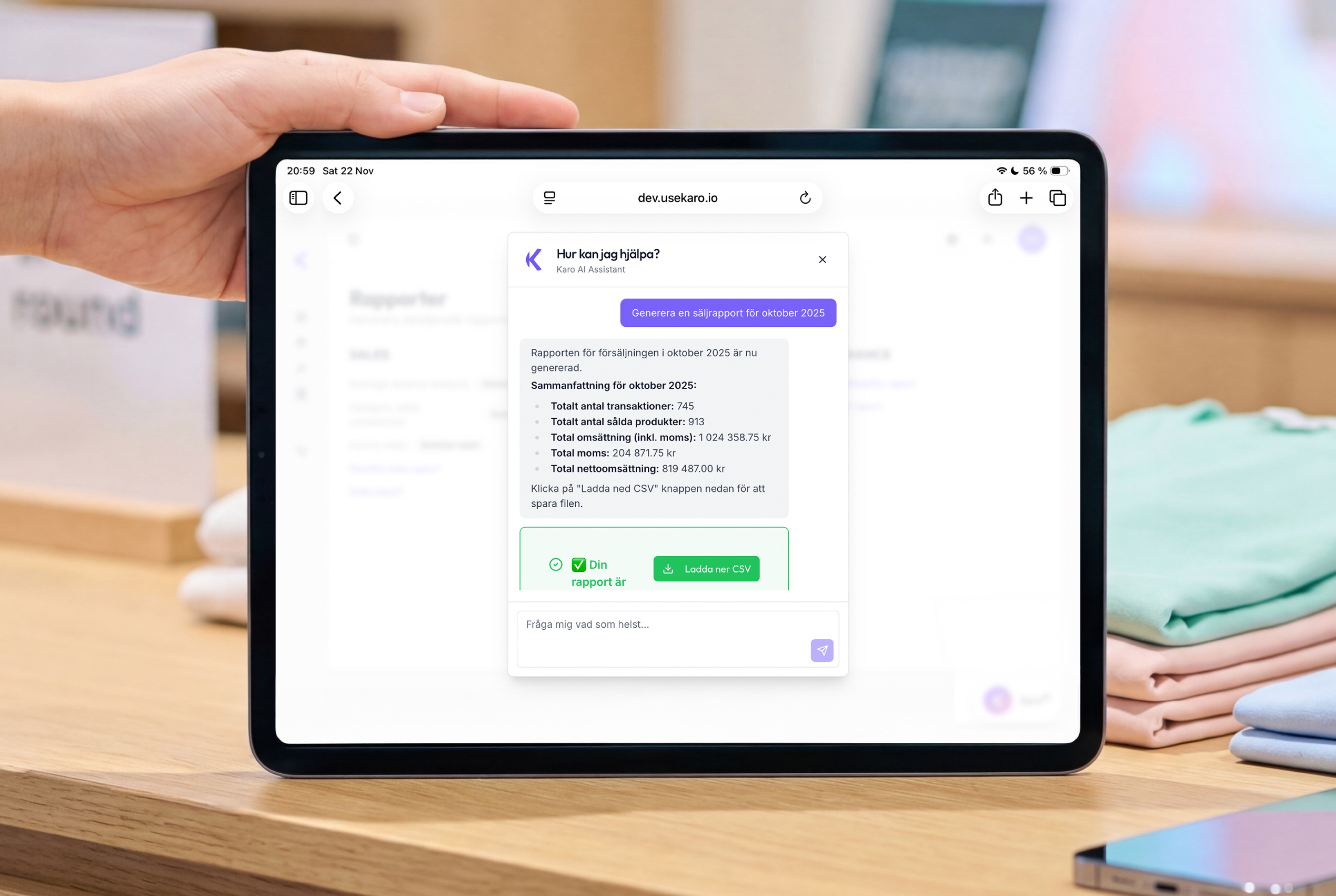 Young man in a green hoodie holding a yellow phone while seated at a table with a tablet.