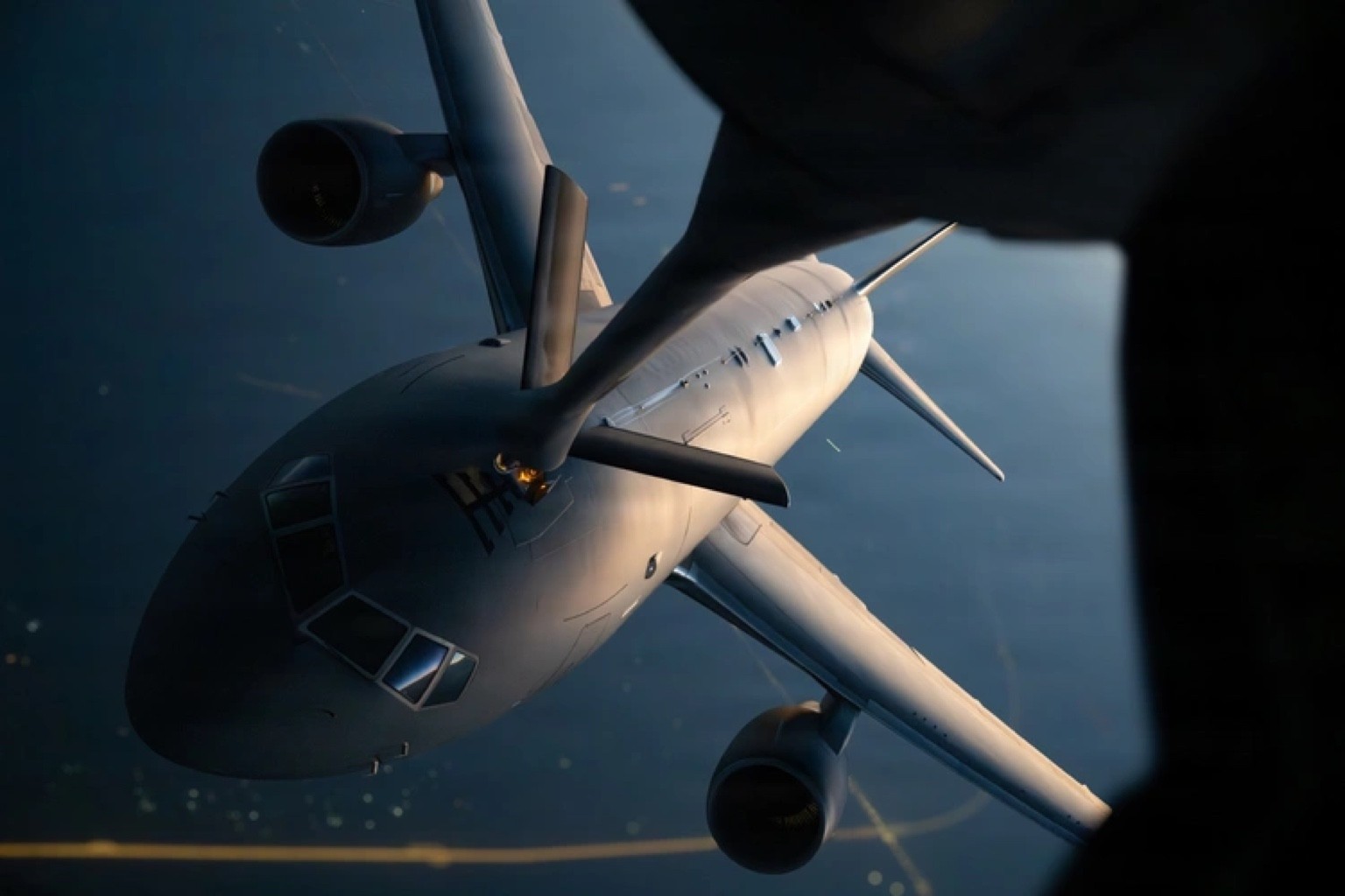 A KC-46A taking fuel from another tanker's refueling boom, seen from above