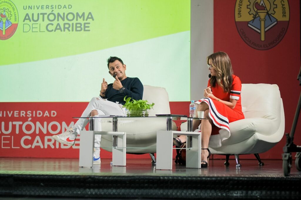 Jorge Baena sentado en el escenario junto a una presentadora durante una conversación en la Universidad Autónoma del Caribe