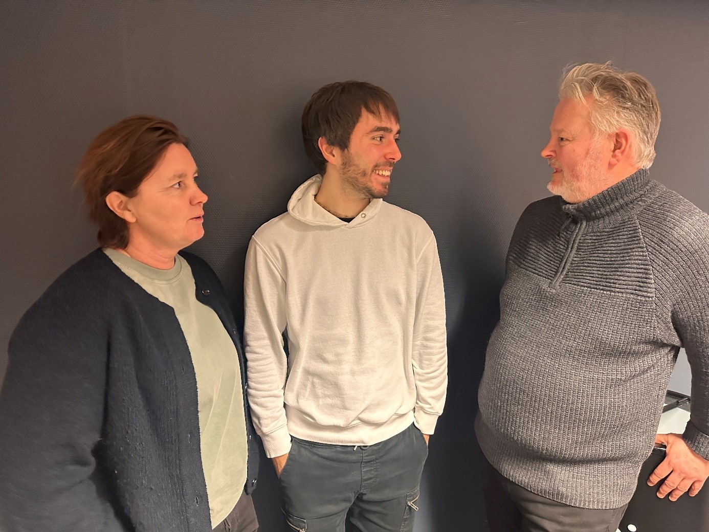 A person wearing a virtual reality headset stands in front of multiple screens, engaged in a digital experience.