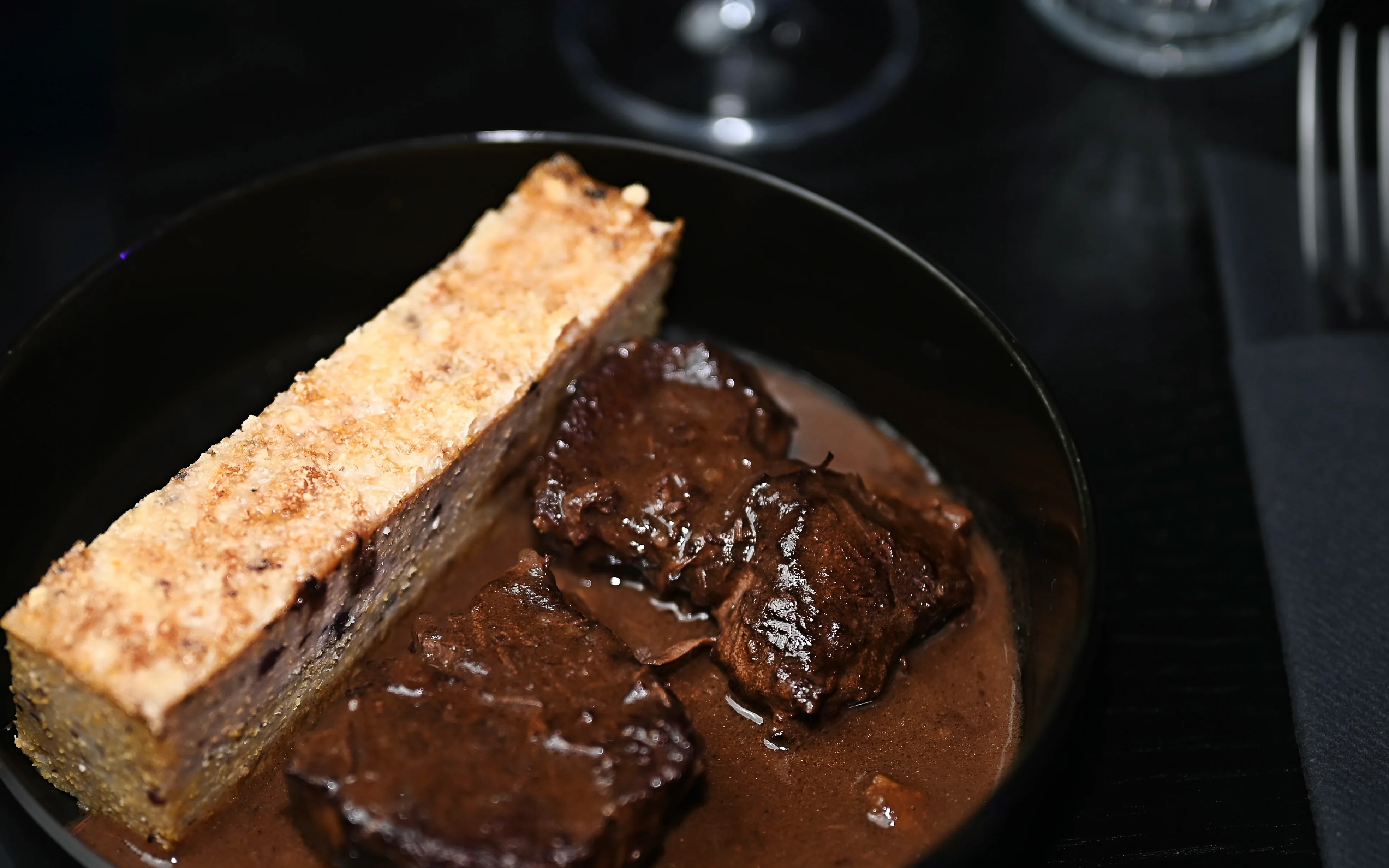 Elevated close-up shot of a gourmet main course dish featuring seared beef medallions covered in a rich dark sauce, showcasing the high-quality dining experience available for private events
