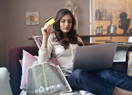 person seated with a laptop computer holding a credit card