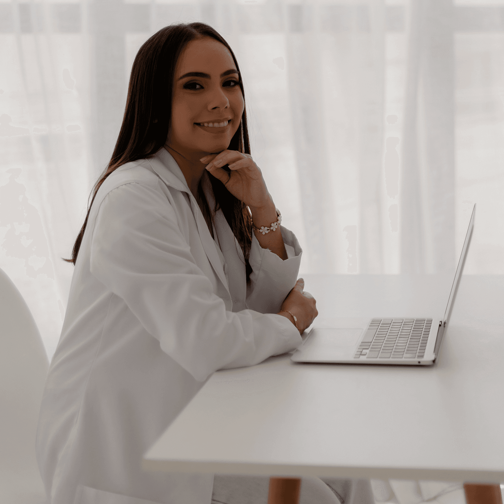 Isa Rodrigues, nutricionista com foco em nutrição para pacientes bariátricos, em seu consultório moderno, usando um laptop para preparar planos alimentares personalizados. Retrato profissional de Isa Rodrigues Nutricionista, dedicada à saúde e bem-estar dos seus pacientes.