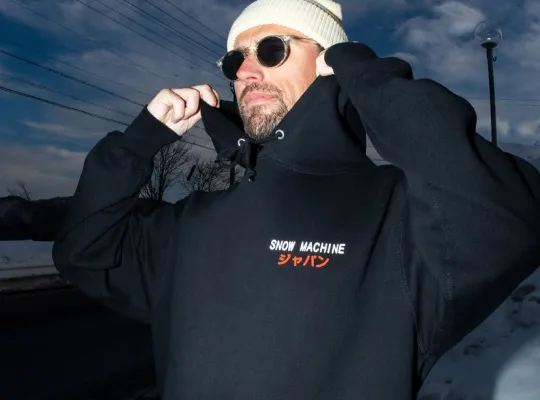 Snow Machine Japan merchandise black hoodie worn with the hood up