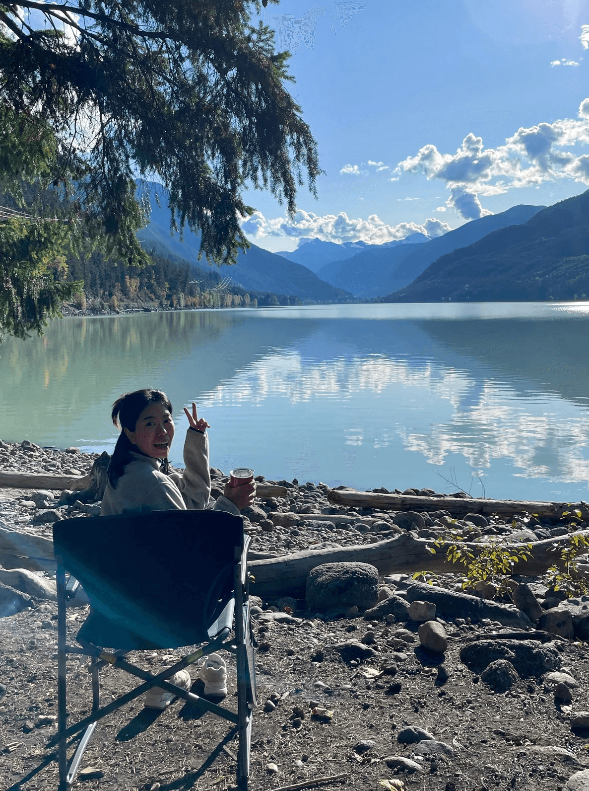 Person wearing a blue puffer jacket and red backpack standing in front of a light blue building on a city street.