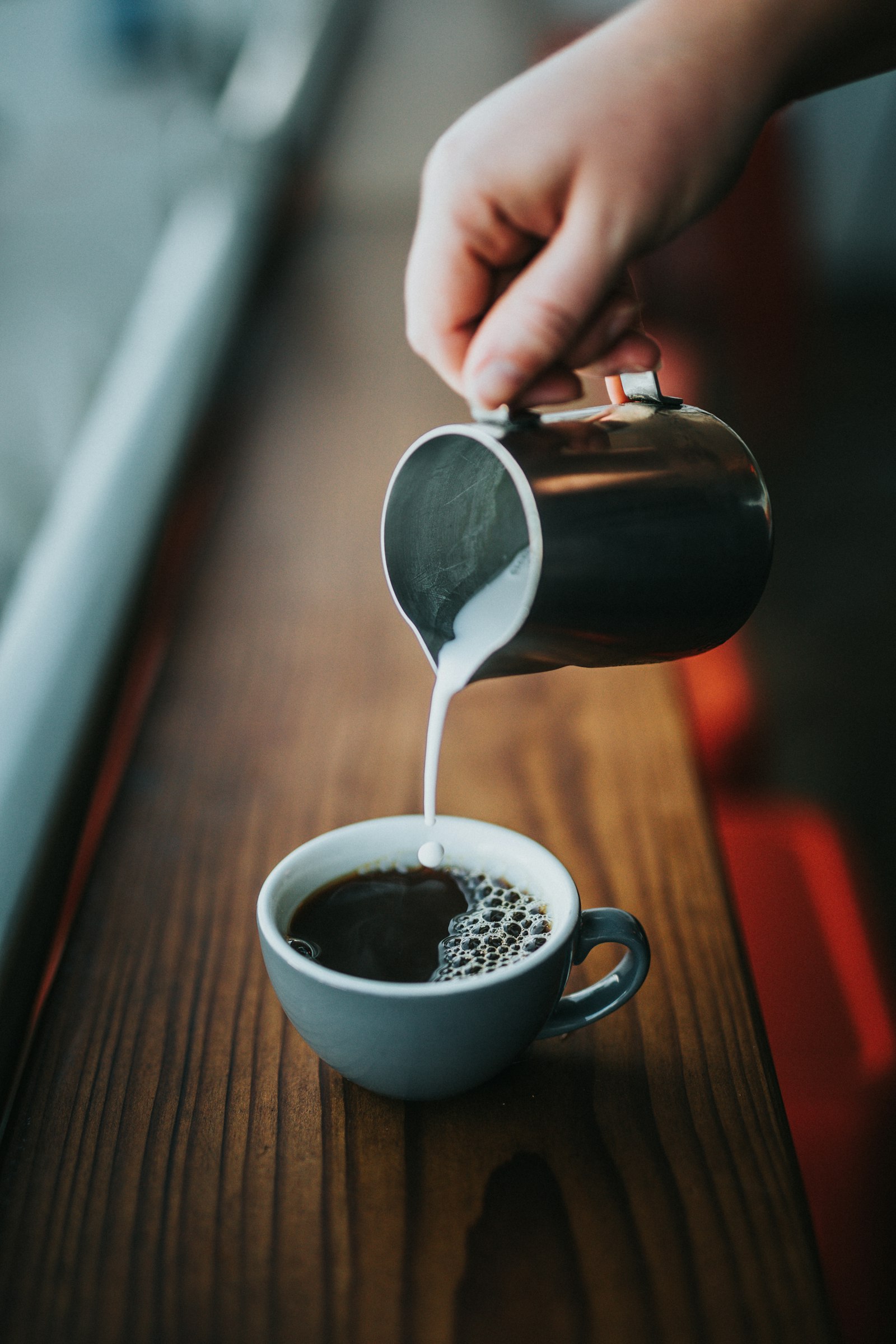 Barista vertiendo leche en una taza en la cafetería Two Guns Espresso de Los Ángeles