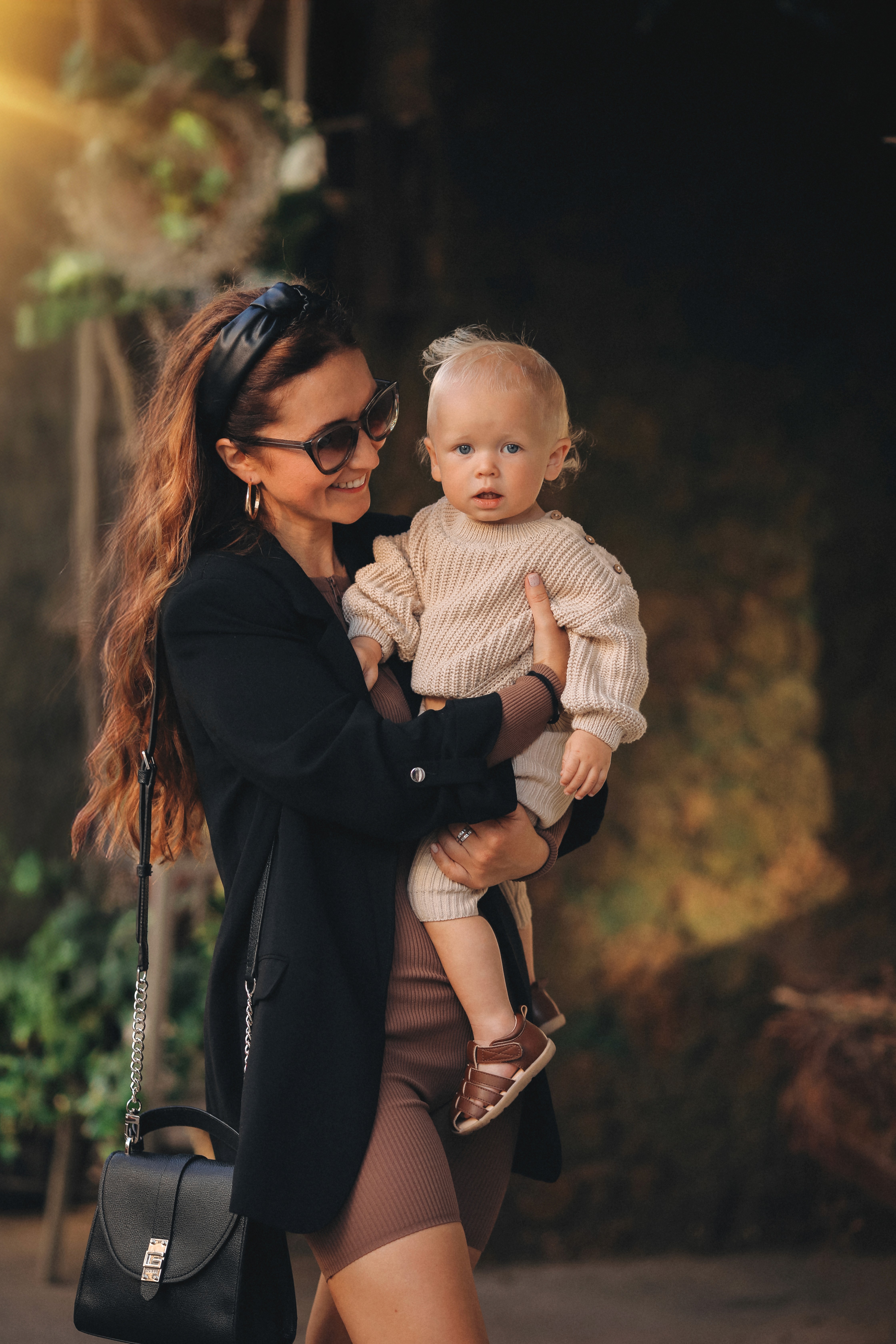 Mother holding her baby during a warm, candid family session in an urban park.