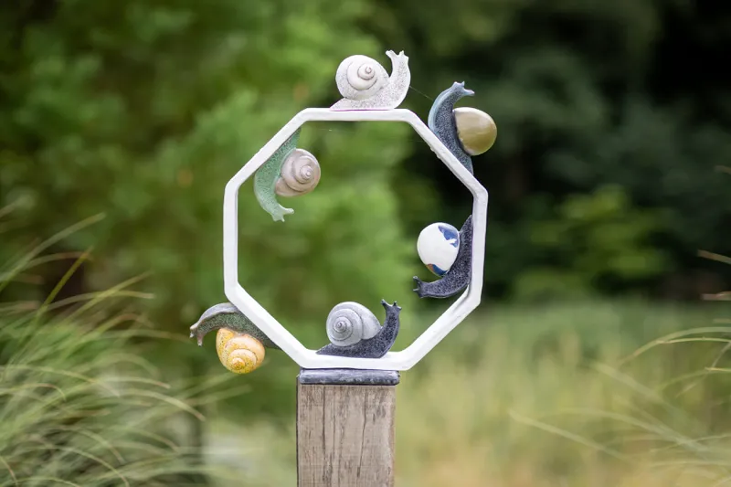 small snail sculptures on the indside and outside of an octagonal structure