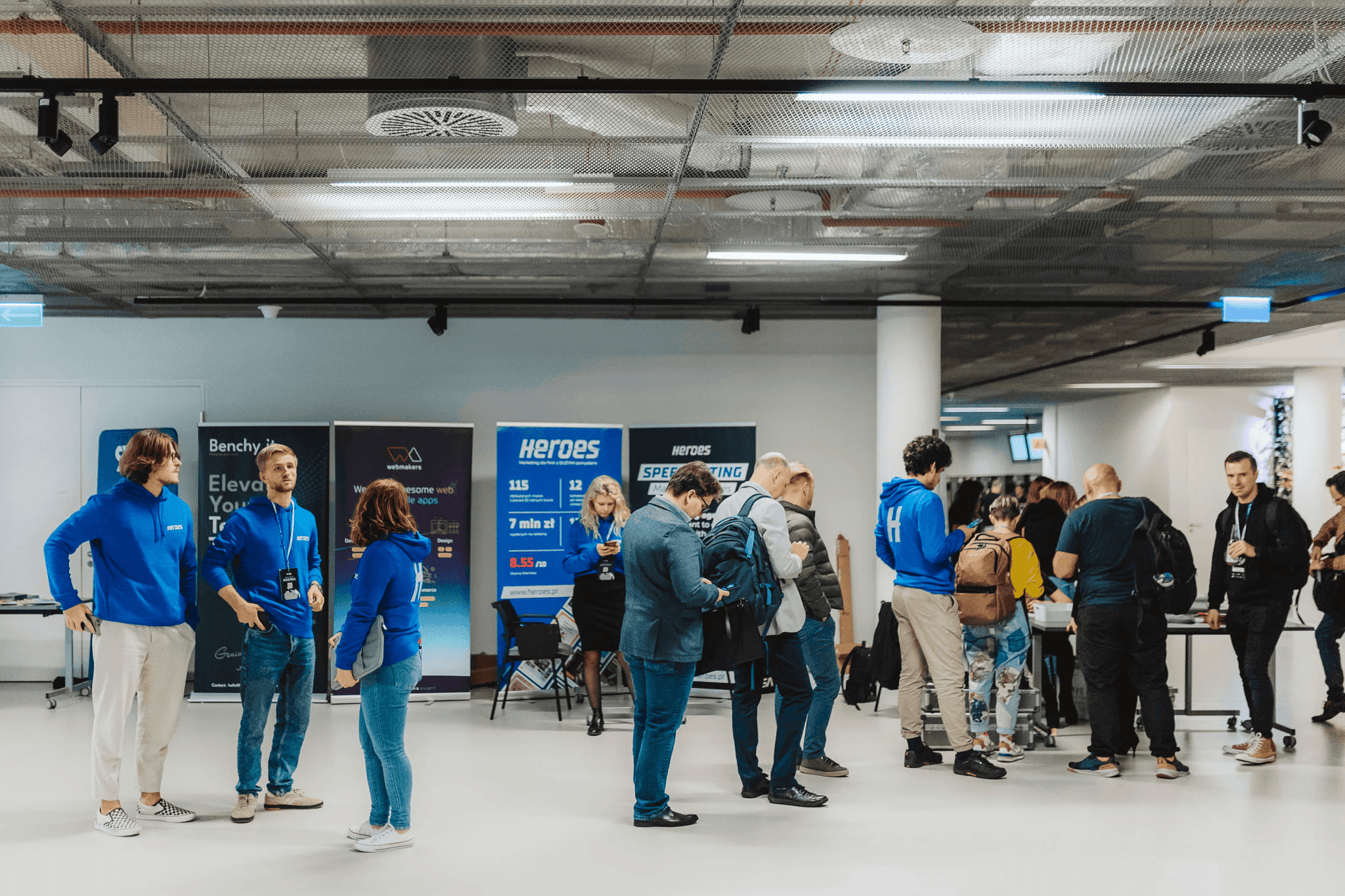 Black and white image of people working at a table with laptops, showing hands gesturing during discussion of digital content displayed on screens, with fabrica® logo in the corner.